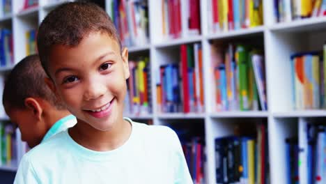 Portrait-of-schoolboy-smiling-in-library-at-school