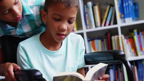 Disabled-schoolboy-reading-book-in-library-at-school