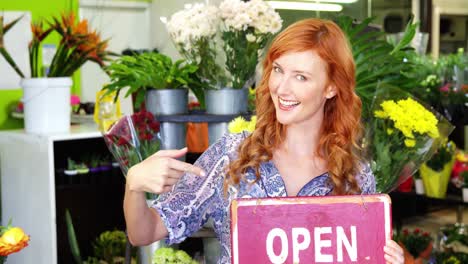 Smiling-florist-holding-open-sign-on-slate-in-flower-shop