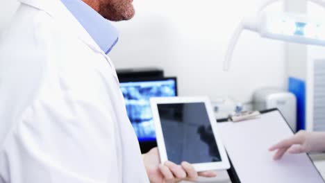 Dentista-Y-Asistente-Dental-Trabajando-En-Una-Tableta-Digital