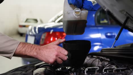 Mechanic-pouring-oil-into-car-engine