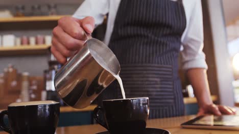 Kellner-Gießt-Milch-In-Kaffeetasse,-Während-Er-Kaffee-Zubereitet
