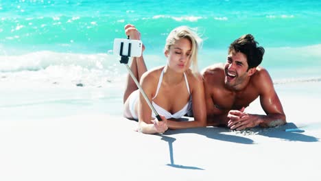 Couple-lying-on-beach-and-taking-a-selfi-from-mobile-phone