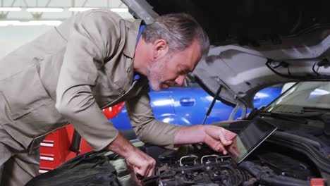 Mechanic-using-digital-tablet-while-servicing-a-car-engine