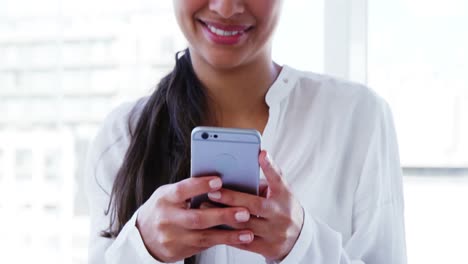 Lächelnde-Frau,-Die-Im-Büro-Ihr-Smartphone-Benutzt