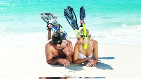 Couple-wearing-diving-mask-and-flippers-lying-on-beach
