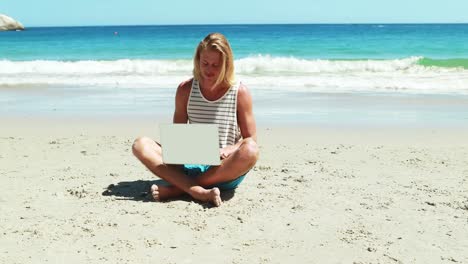 Man-using-laptop-on-beach