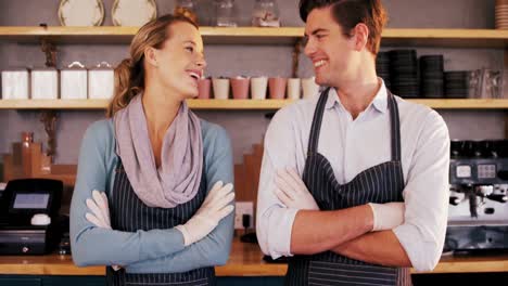 Waiter-and-waitress-standing-with-arms-crossed-and-smiling-at-each-other