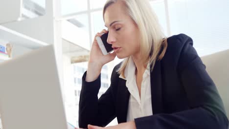 Businesswoman-talking-on-the-mobile-phone-at-her-desk