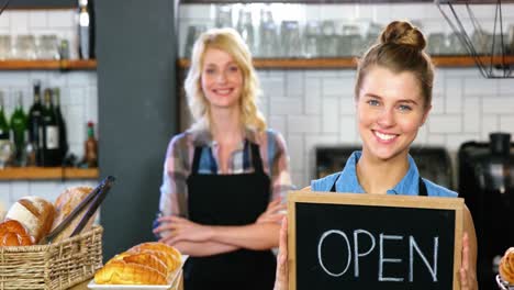 Portrait-of-waitress-standing-with-open-sign-board
