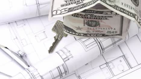 Close-up-of-plans,-dollar-house-and-keys-turning