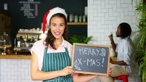 Portrait-of-waitress-standing-with-merry-x-mas-board