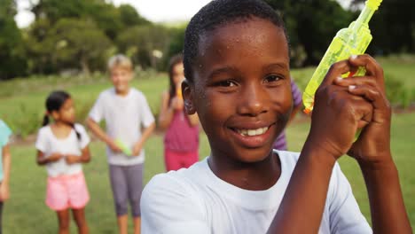 Portrait-of-smiling-boy-playing-with-water-gun