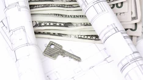 Close-up-of-plans,-dollars-and-keys-turning