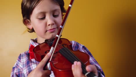Schoolboy-playing-violin-in-classroom-at-school