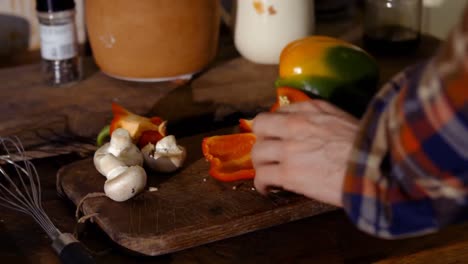 Man-chopping-a-vegetables-on-chopping-board-in-kitchen