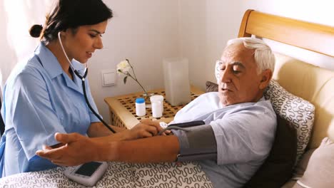 Nurse-checking-blood-pressure-of-senior-man-in-bedroom