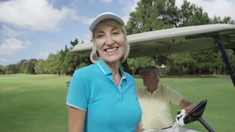 Portrait-of-female-golfer-standing-near-golf-buggy-