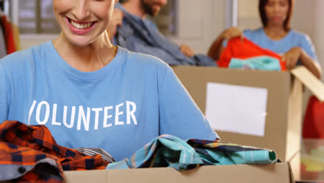 Voluntaria-Femenina-Sosteniendo-Ropa-En-Caja-De-Donación