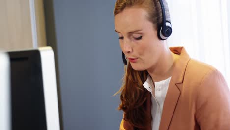Businesswoman-talking-on-a-headset-at-desk