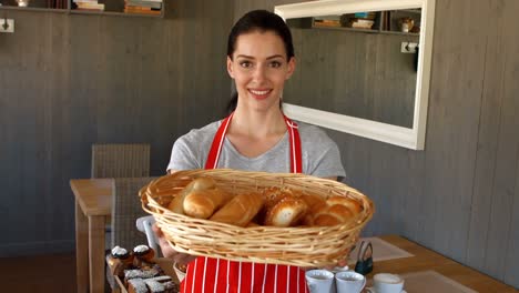 Portrait-of-female-baker-holding-baguettes-in-basket