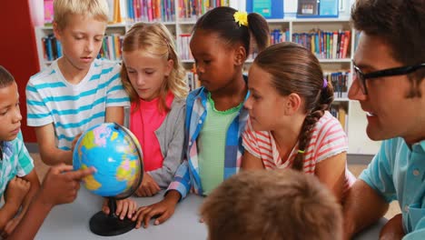 Kids-and-teacher-looking-at-globe-in-library