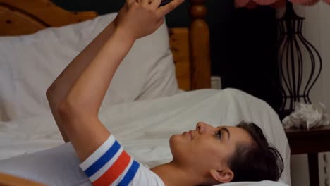 Woman-using-mobile-phone-while-lying-on-bed