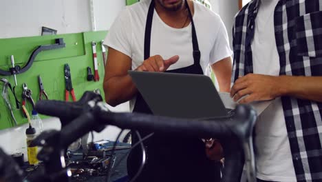 Mechanics-discussing-on-laptop-in-workshop