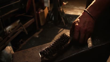 Mid-section-of-blacksmith-holding-wire-brush