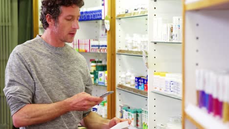 Customer-using-mobile-phone-with-a-bottle-of-drug-in-hand