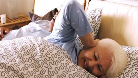 Man-snoring-and-woman-covering-her-ears-while-sleeping-on-bed