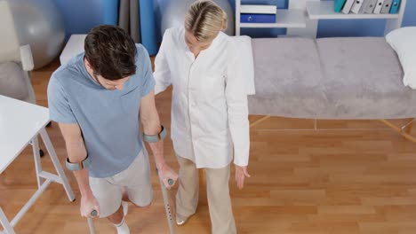 Fisioterapeuta-Ayudando-Al-Paciente-A-Caminar-Con-Muletas.