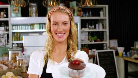 Portrait-of-waitress-holding-a-plate-with-a-cupcake