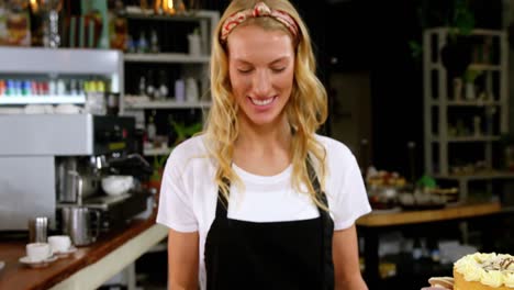 Portrait-of-smiling-waitress-standing-with-dessert