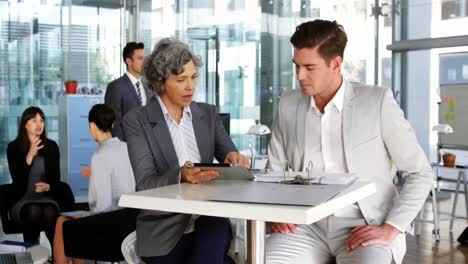 Businesswoman-discussing-over-digital-tablet-with-colleague