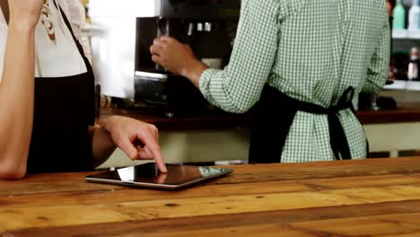 Waitress-standing-at-counter-using-digital-tablet