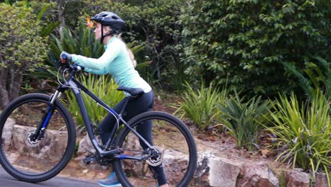 Ciclista-Femenina-Caminando-Con-Bicicleta-De-Montaña-En-El-Bosque