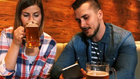 Paar-Benutzt-Mobiltelefon,-Während-Es-Ein-Glas-Bier-Trinkt