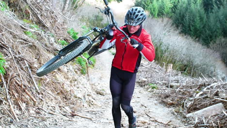 Mountain-biker-carrying-bicycle-in-forest