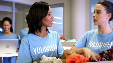 Dos-Voluntarias-Sosteniendo-Ropa-En-Caja-De-Donaciones