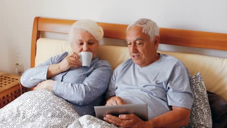 Ältere-Frau-Benutzt-Digitales-Tablet-Und-Mann-Trinkt-Eine-Tasse-Kaffee