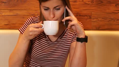 Woman-having-a-coffee-while-talking-on-phone