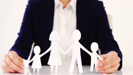Businesswoman-holding-paper-cut-out-of-a-family