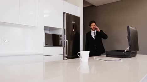 Businessman-talking-on-mobile-phone-in-kitchen