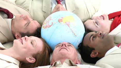 Business-team-on-floor-in-a-circle-with-a-terrestrial-globe-in-the-center