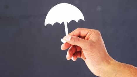 Hand-holding-paper-cut-out-of-a-umbrella