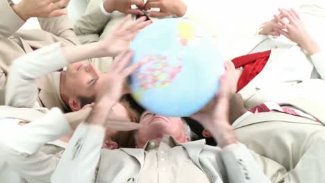 Business-team-on-floor-in-a-circle-holding-a-terrestrial-globe