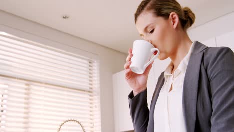 Woman-drinking-coffee-in-kitchen