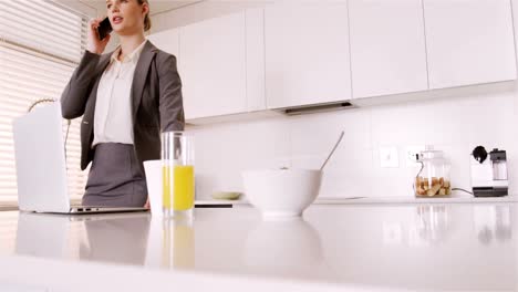 Woman-talking-on-mobile-phone-in-kitchen