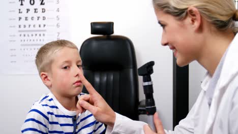 Female-optometrist-examining-young-patient-with-ophthalmoscope
